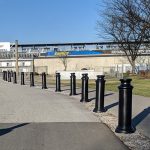 Black plastic Pawn Decorative Bollard Covers lining a sidewalk